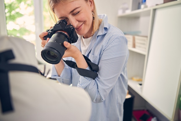 Positieve vrouw die een camera gebruikt en professionele foto's maakt in de kamer