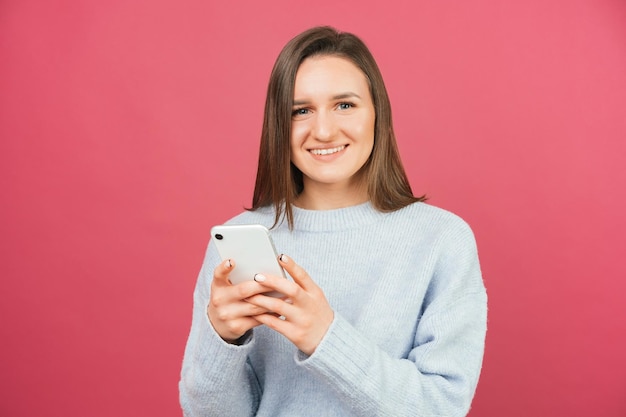 Positieve vrouw gebruikt smartphone terwijl ze naar de camera lacht