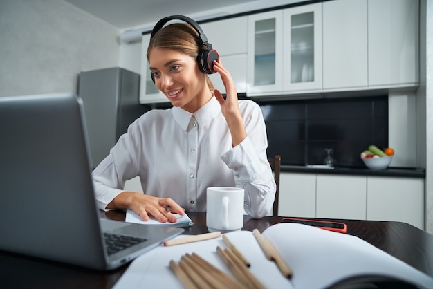 Positieve vrouw in koptelefoon met videochat op laptop