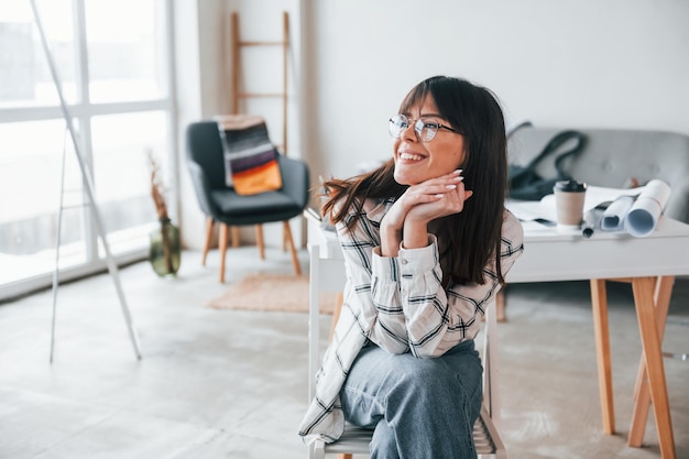 Positieve vrouw lacht Jonge vrouwelijke freelance werknemer is overdag binnenshuis in huis