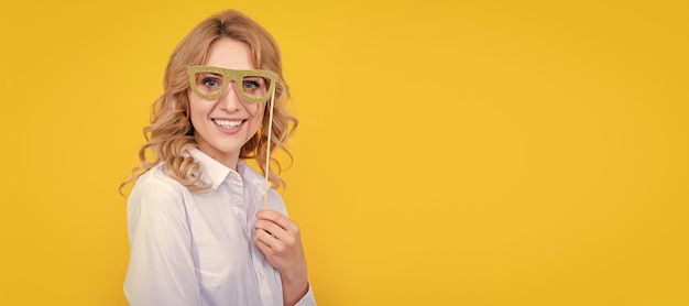 Positieve vrouw met grappige feestbril op gele achtergrond Vrouw geïsoleerde gezichtsportretbanner met mock-up kopieerruimte