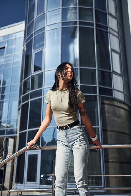 Positieve vrouw met tatoeage op arm veel plezier buitenshuis tegen bedrijfsgebouw op zonnige dag