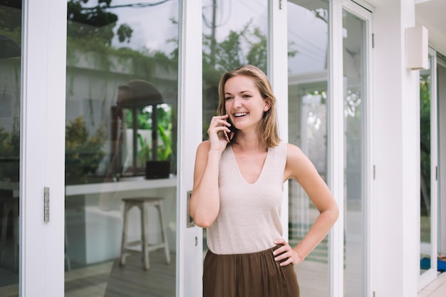 Positieve vrouw praten op mobiele telefoon in de tuin