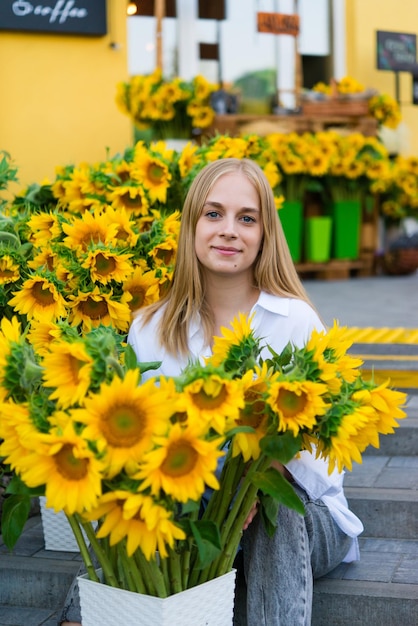 Positieve vrouwelijke bloemist die verse bloemenregeling in bloemenwinkel houdt. Heldere zonnebloemen. Bloem