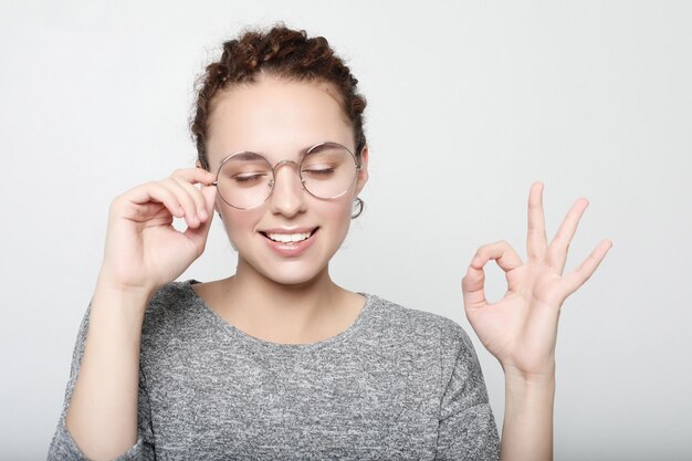 Positieve vrouwelijke student draagt grijze trui ronde bril