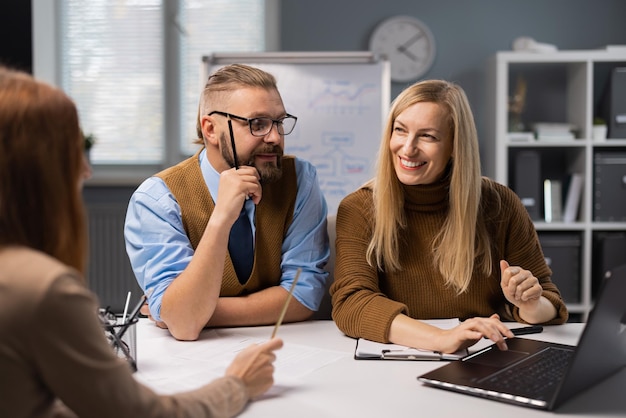 Foto positieve zakencollega's die samen aan een bureau zitten met een moderne laptop en een werkgesprek voeren concept van samenwerkingssucces en technologie