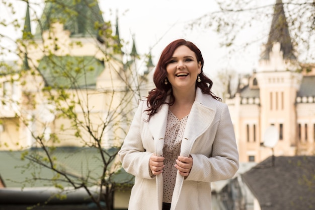 Positive adult model wearing trendy blouse and coat, posing at the street, space for text