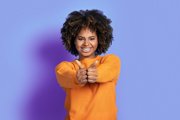 Photo positive african american woman showing thumb ups on purple