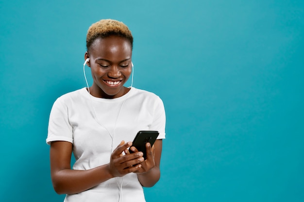 Positive african girl listening music with headphones.