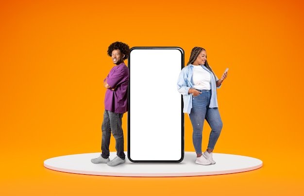 Positive african man and woman standing by big phone