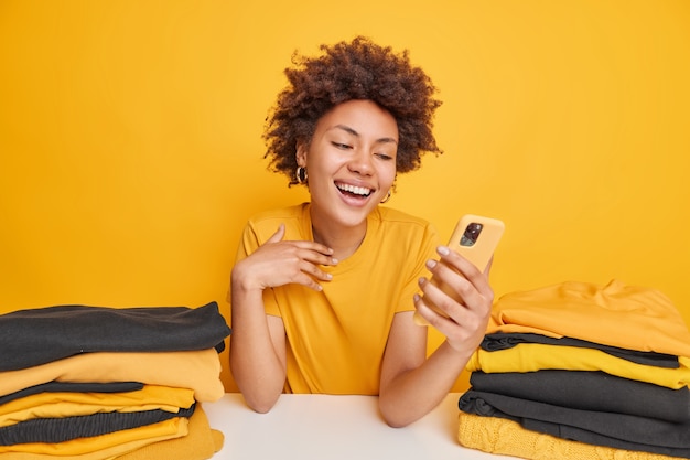 Positive Afro American woman holds mobile phone gets text message 