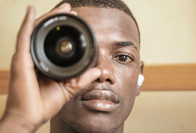 Позитивный черный парень с объективом камеры на глазу