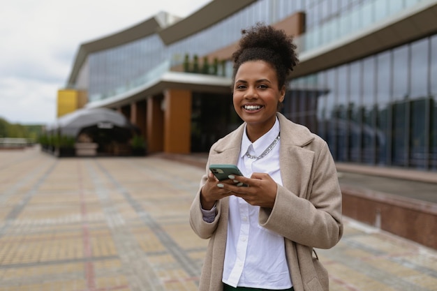 Positive black young woman with a wide smile against the background of a modern city building with a