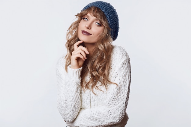 Positive blond woman in sweater and hat 