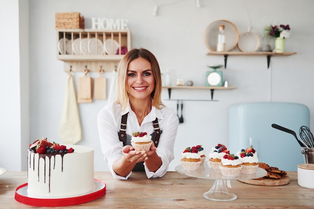 Positive blonde with her homemade delicious cookies and cake in the kitchen.