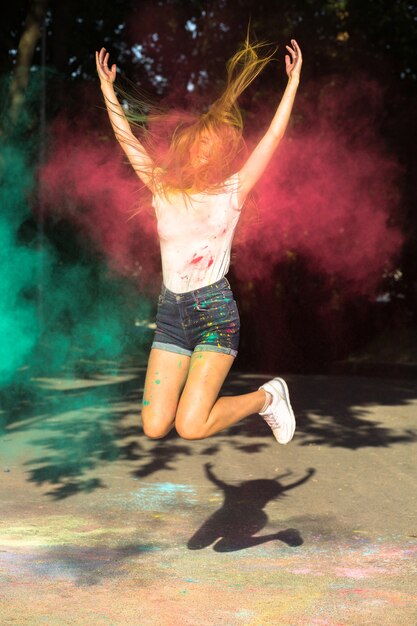 Positive blonde woman jumping with vibrant colors exploding around her