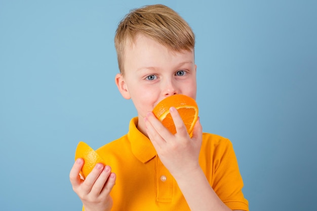 Positive boy holding a cut half of an orange Positive emotions