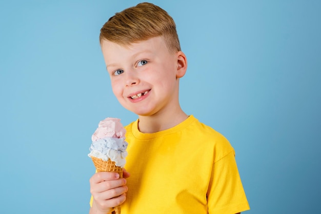 Positive boy holding ice cream on a blue background Health benefits ice cream concept