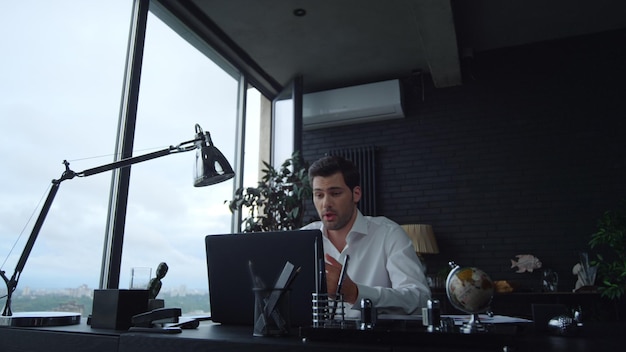 Positive businessman talking with business partner during video chat in office