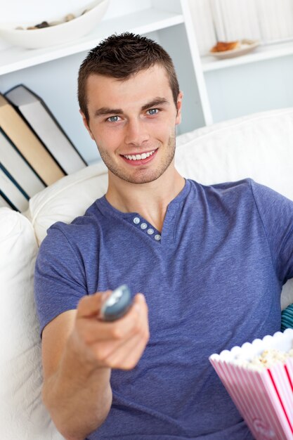 Photo positive caucasian man holding a remote looking at the camera