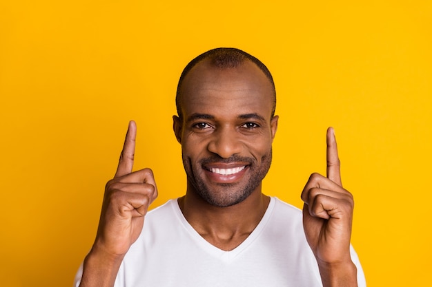 Позитивный веселый афро-американский парень указывает указательным пальцем вверх копией пространства указывает на рекламу промо рекомендуют выбрать одежду в хорошем стиле, изолированный яркий блеск на цветном фоне