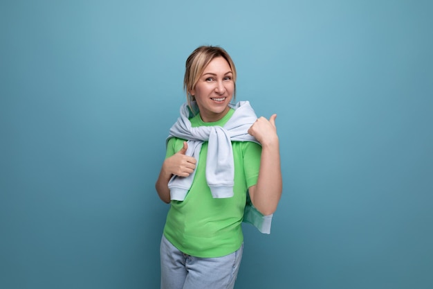 Positive cheerful young woman in casual outfit on blue background with copy space