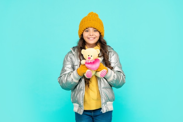 Positive child wearing warm clothes on blue background. express positive emotion.