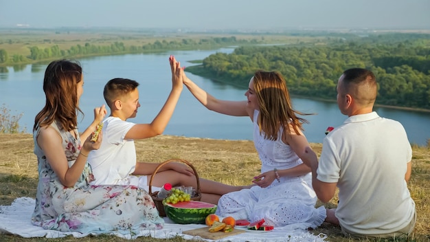 Bambini e genitori positivi ballano al picnic vicino al fiume