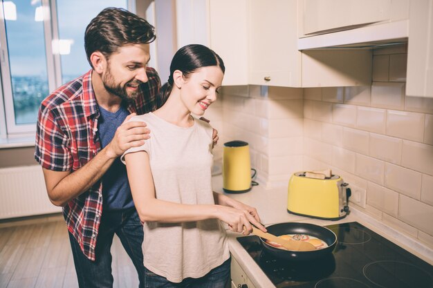 Positive couple stands in kitchen.