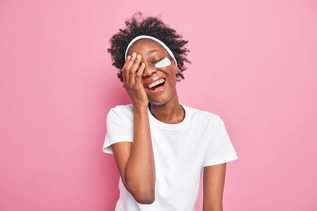 Positive dark skinned woman has overjoyed carefree expression laughs at something