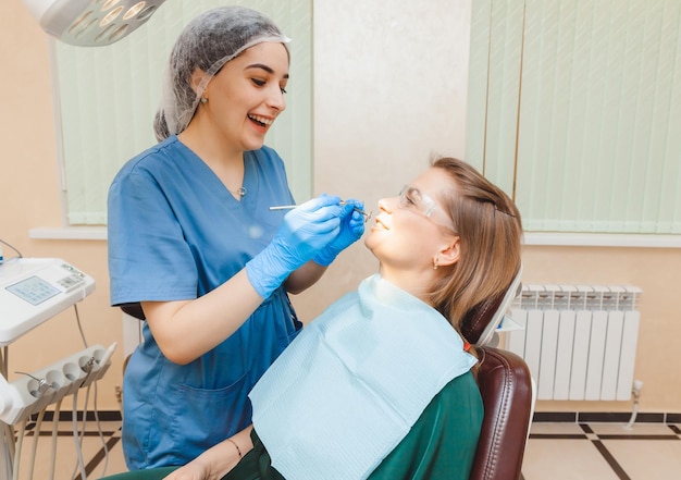 Photo a positive darkhaired woman sits in the dentist's office during a checkup dentist examining woman's teeth