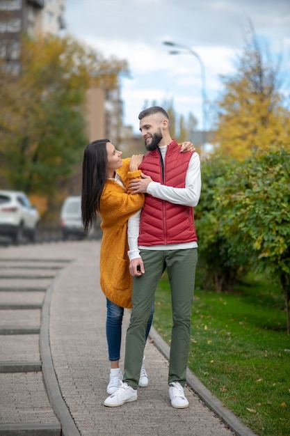 Positive delighted couple having a great time while walking on the street