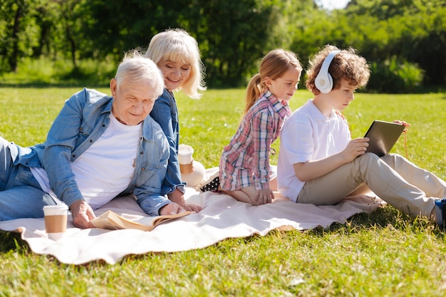 Positive delighted couple sitting next to each other, smiling and reading book