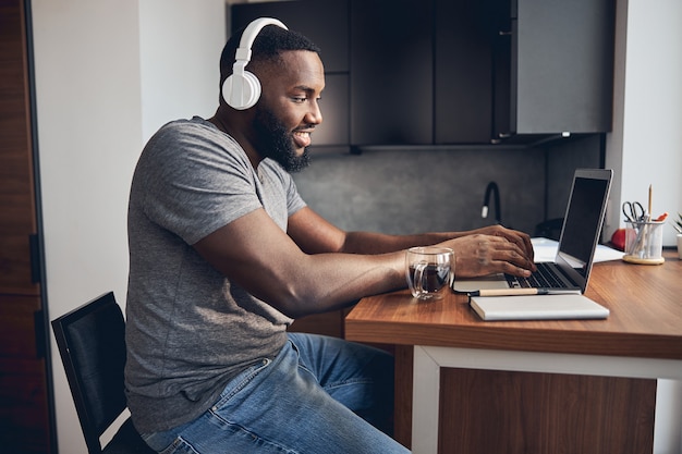 Photo positive delighted man sitting in front of his laptop