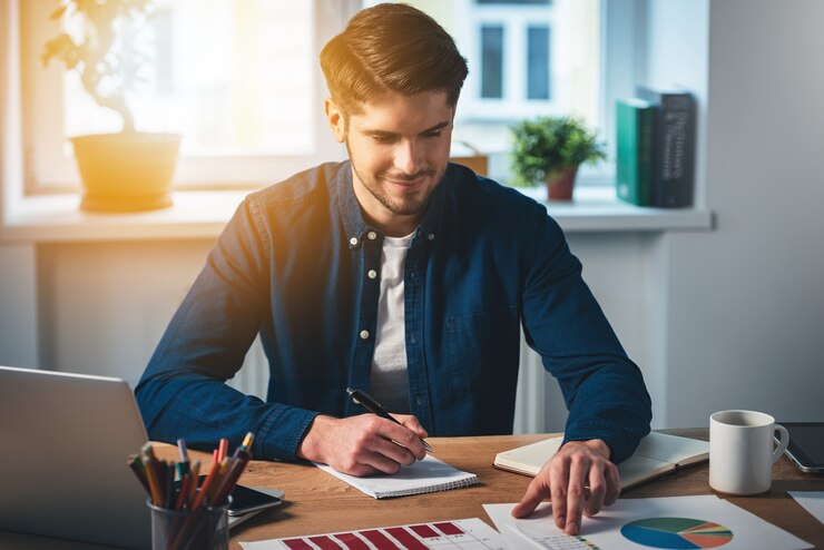 Photo positive dynamic! cheerful young handsome man working with charts with smile 