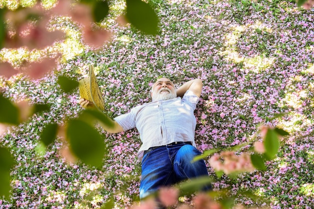 Positive emotions Cheerful pensioner Happy smiling grandpa looking up Guy enjoying life United with nature Good mood Happy old age Mental health Happy man under sakura tree looking upwards