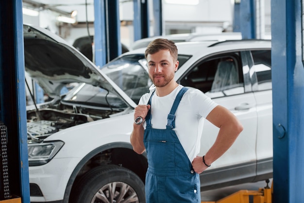 Positive emotions. Employee in the blue colored uniform works in the automobile salon