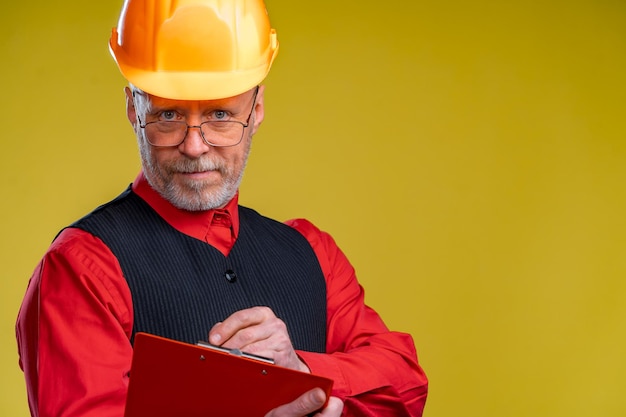 Positive engineer in a helmet on a yellow background