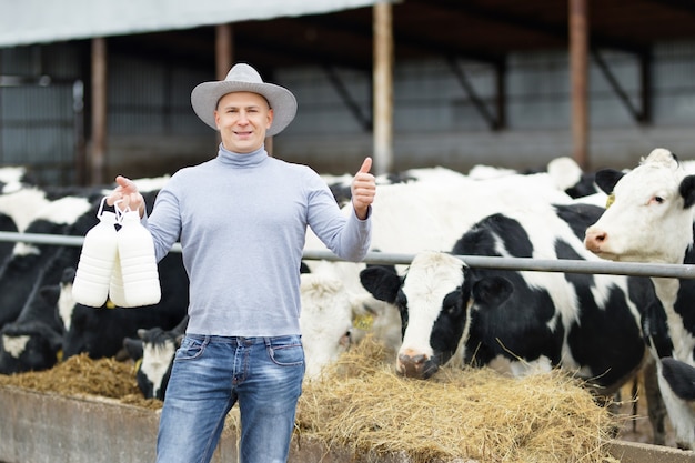 Positive farmer with milk of cow farm