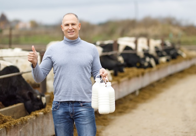 Positive farmer with milk of cow farm