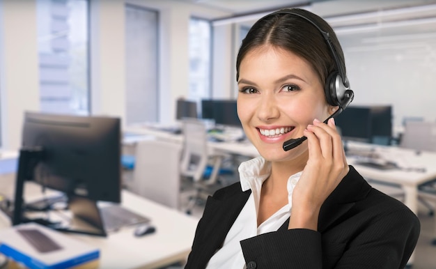 Photo positive female customer services agent with headset working in call center