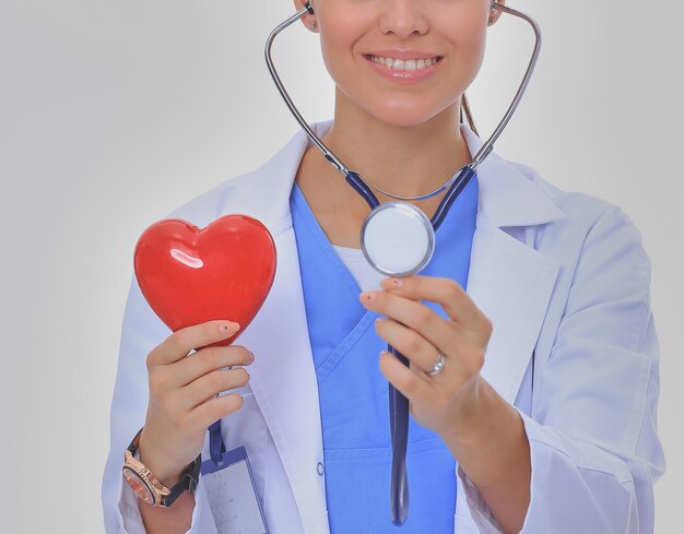 Positive female doctor standing with stethoscope and red heart symbol isolated Woman doctor