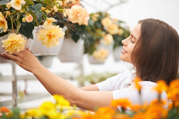 Positive female florist checking growth of plants in pots