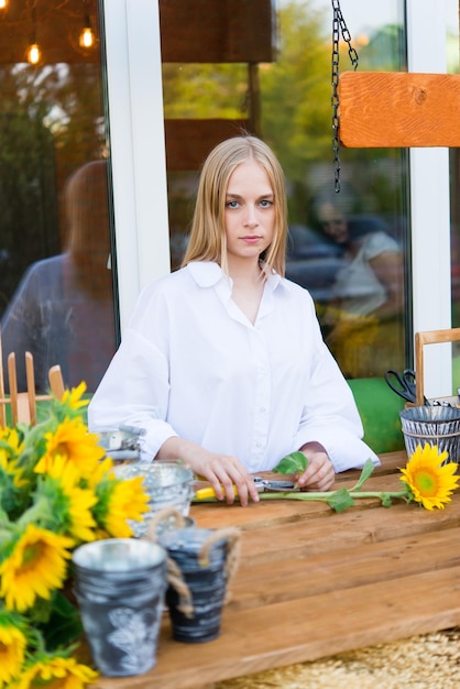 フラワー ショップで新鮮な花のアレンジメントを保持している肯定的な女性の花屋。明るいひまわり。花