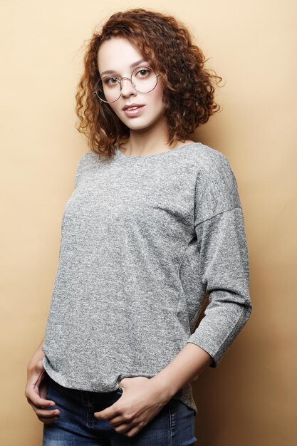 Positive female student wears grey sweater round glassespeople\
studying success and achievements