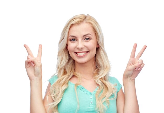 positive gesture and people concept - smiling young woman or teenage girl showing peace hand sign with both hands