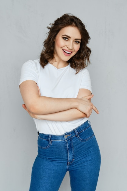 Positive girl in jeans, white t-shirt and red stilettos posing