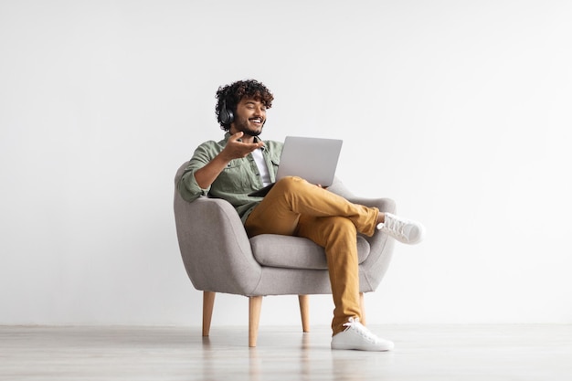 Photo positive handsome indian having video conference using notebook