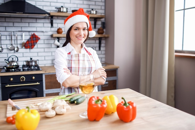 Donna adulta felice positiva che posa sulla macchina fotografica in cucina