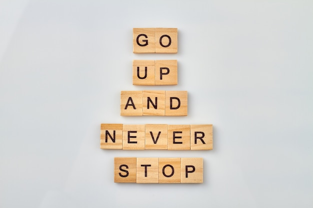 Positive idea for improving life. Go up and never stop. Wooden cubes isolated on white background.